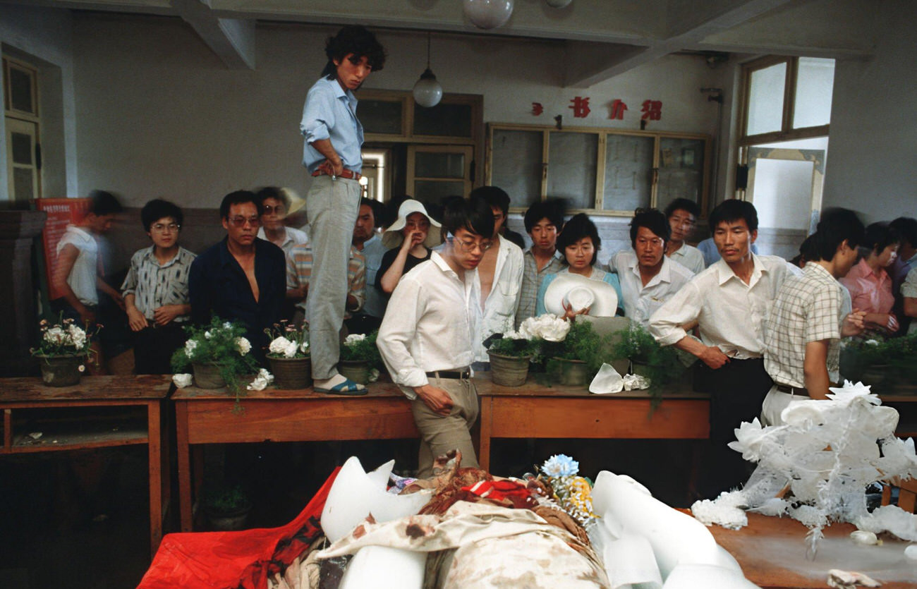 Onlookers examine the dead body of a protestor lying in a temporary morgue, 1989.