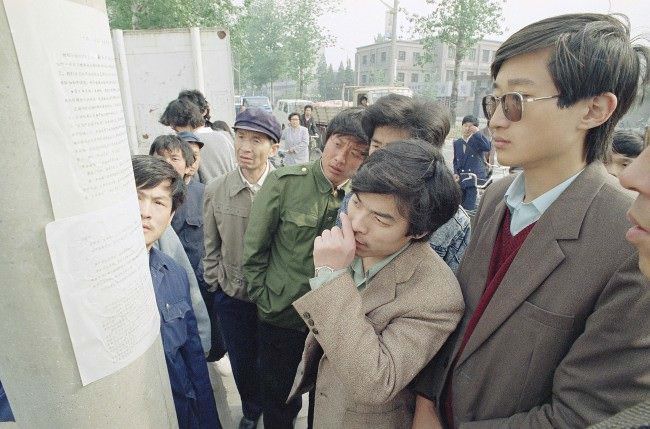 Beijing residents read a copy of a newspaper printed by students and placed on a streetlight pole near the Beijing University campus describing the student demonstrations on Friday and Saturday at Tiananmen Square, April 24, 1989.