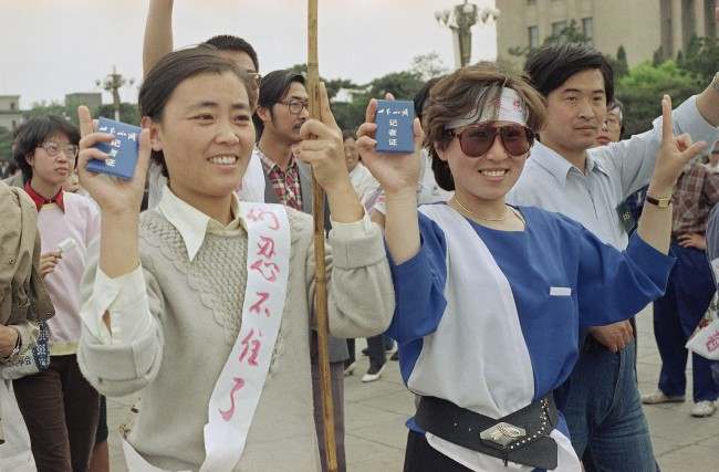 Employees of CCTV, Central China Television, flash their press cards as they join student strikers for democracy in Beijing’s Tiananmen Square at night, Tuesday, May 16, 1989.