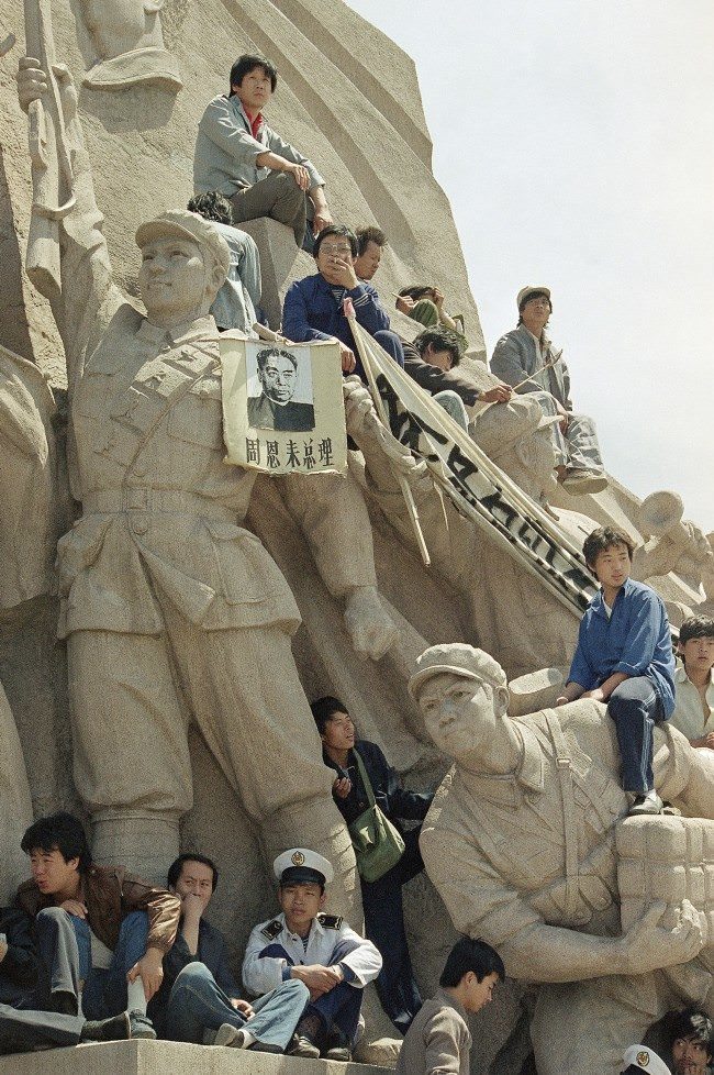 Beijing University students use a monument to the late chairman Mao Tse-Tung at his tomb in Tiananmen Square to press their case for democratic reforms in Beijing, Friday, May 19, 1989. The picture hanging on the statue is the late Premier Chou En-Lai.