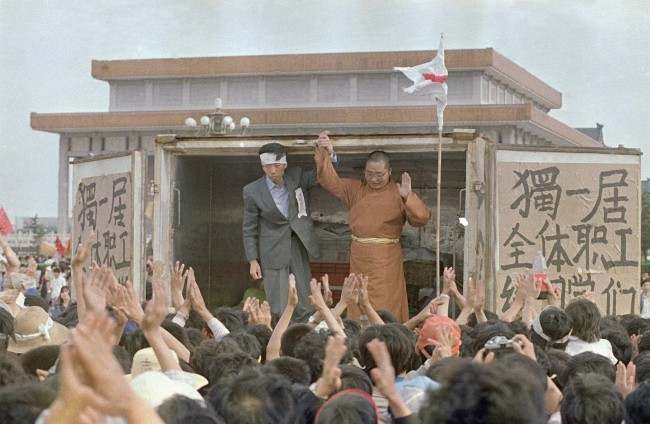 Li Nan, left, of Du Yiju Restaurant, and Yuan Chi, a monk with the China Buddhist Association, receive cheers from students in Tiananmen Square, Sunday, May 21, 1989, Beijing, China. They have donated over $53,000 worth of food to the protestors in the square.