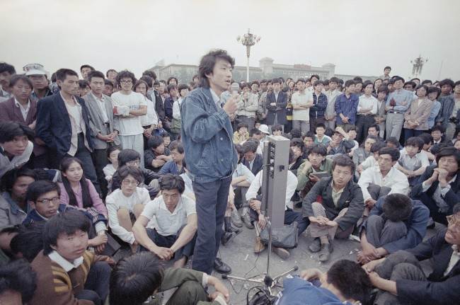 Beijing University students listen as a strike spokesman details plans for a rally in Tiananmen Square, which they have occupied for the last two weeks, Sunday, May 28, 1989, Beijing, China.