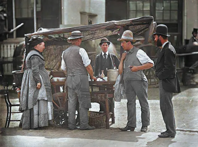 Crowds gather around a shellfish stand, 1890s.