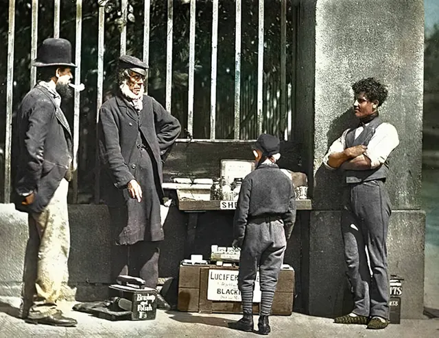 Three men and one young boy gather around a shoeshine stand, 1890s.