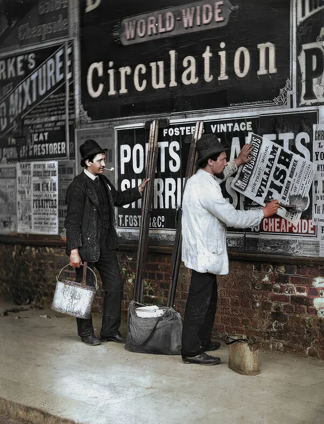 Two men are seen working on posting advertisements, 1890s.