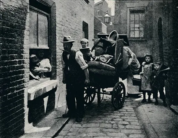 In the slums, families had to carry all their belongings when forced to move due to eviction. This photograph from around 1901 captures a family during such a relocation.