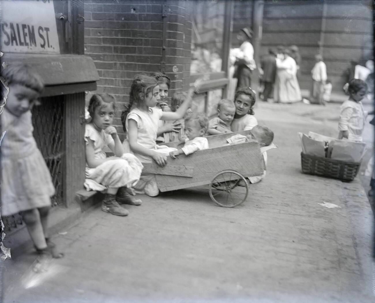 Poor children playing with each other, parents in background.