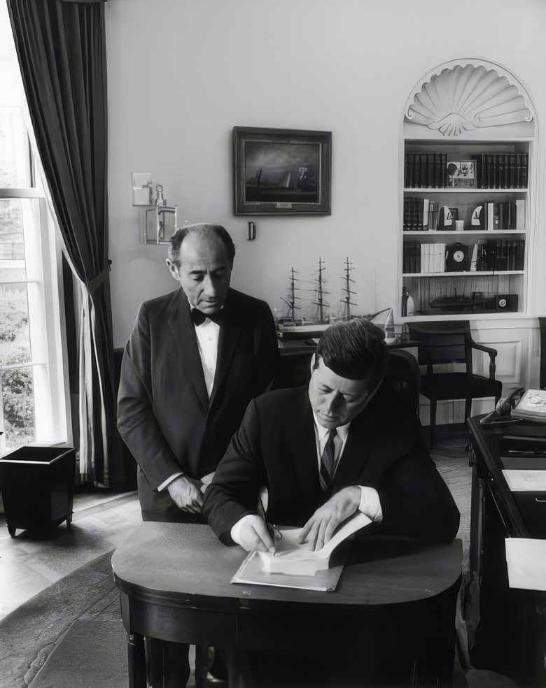 President John F. Kennedy signs Alfred Eisenstaedt's autograph book after a portrait session in the oval office, 1962.