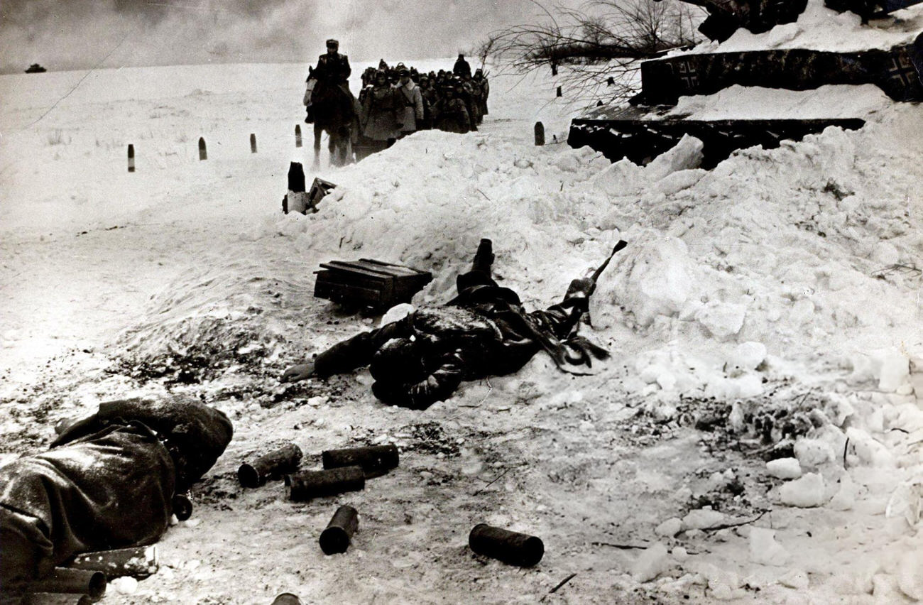 A dead Russian soldier lies by a wrecked German tank as a troop of Russian soldiers pass during the battle of Stalingrad, 1942.