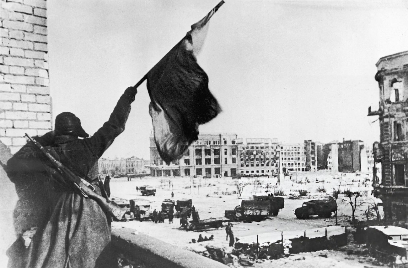 A Russian soldier waves a flag while standing on a balcony during the Battle of Stalingrad, 1942.