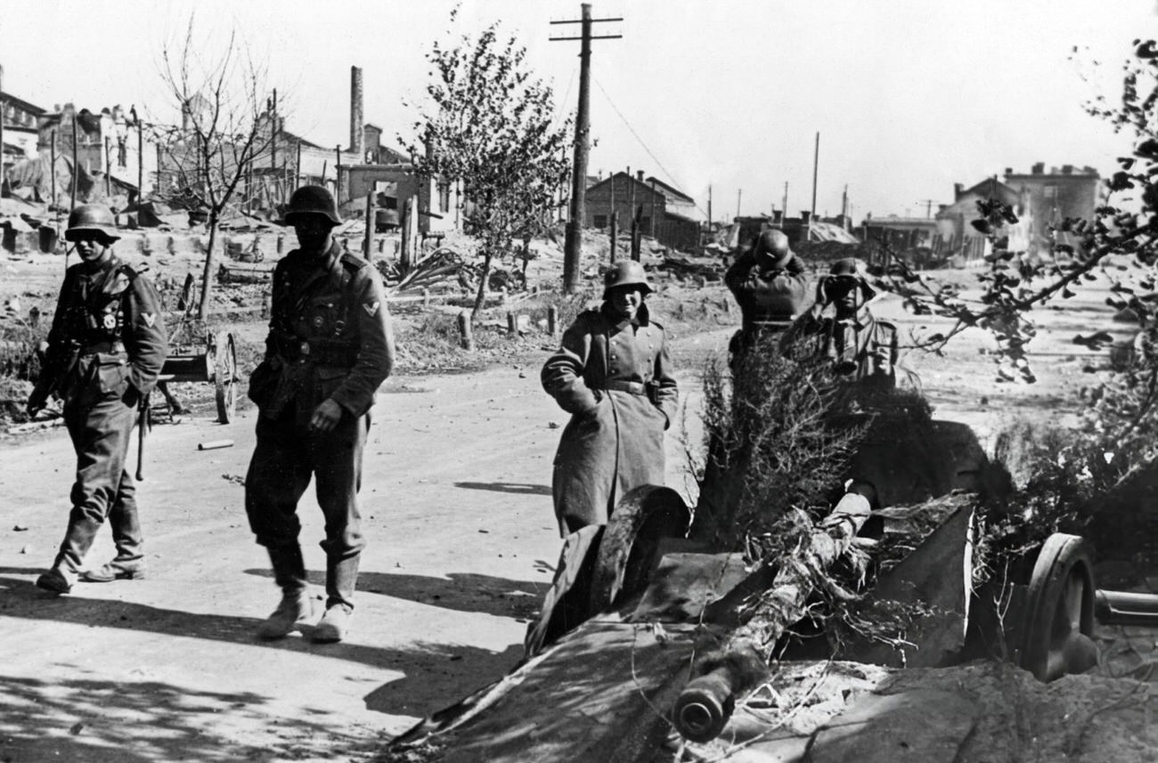 German soldiers checking the horizon next to a camouflaged antiaircraft piece among the ruins of a street in Stalingrad, 1942.