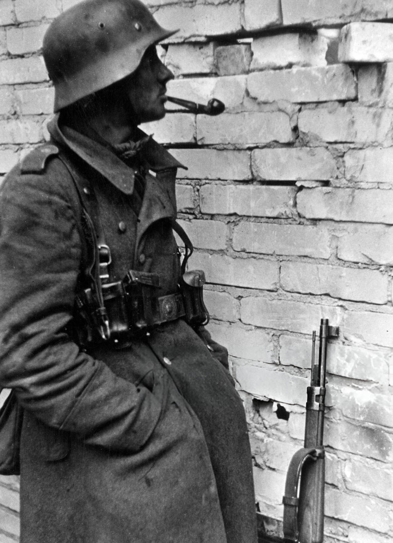 German sentry observing Russian soldiers moves through a wall's hole in Stalingrad, 1942.