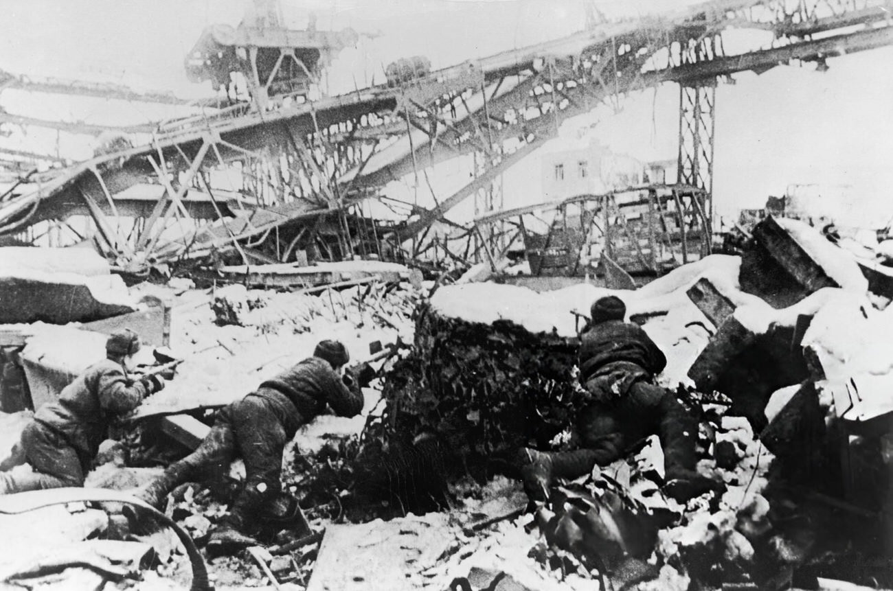 Russian soldiers aim their rifles from behind snow-covered rubble during the Battle of Stalingrad, 1942.