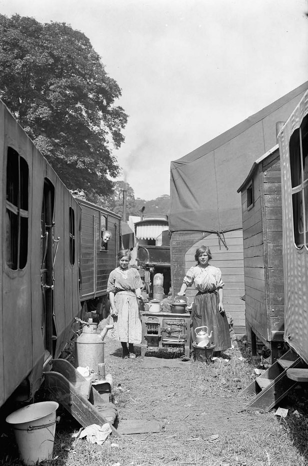 Outdoor stove. Two girls stood next to an old stove in amongst a group of caravans.