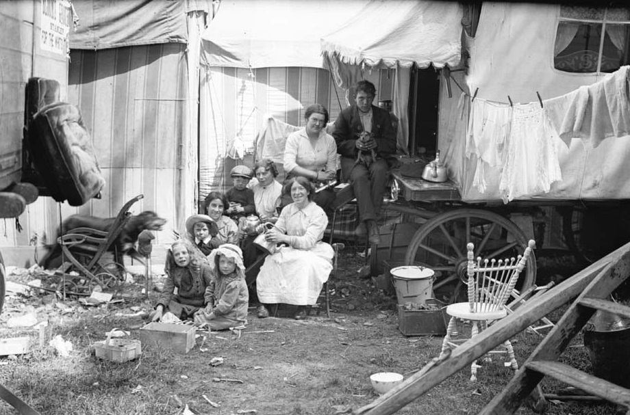 Group of travelers. This group of fair/circus travelers are sat amongst caravans and big top style tents.