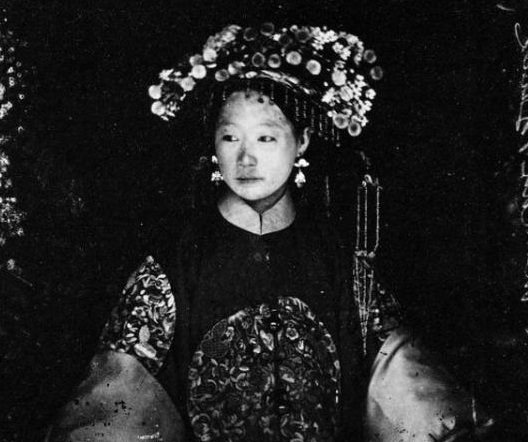 In a photograph taken in Peking around 1867, this sumptuously dressed Manchu bride looks as though she's supporting quite a weight on her head with that headdress.