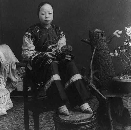 Seated here with her feet up is a ‘lily-footed’ woman – a term for those who had their feet bound as children. In the Chinese culture of the time, the size of a girl’s feet were as important (if not more so) than the appearance of her face.