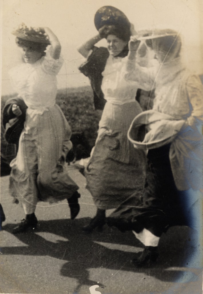 In temperatures of 90 degrees the wind blowing off the sea must have been refreshing even though it also presented a challenge to these three women who are literally hanging on to their hats.