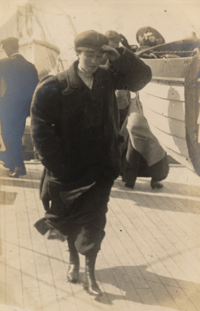 The woman of the couple on the ferry, wearing a masculine-looking coat and hat.