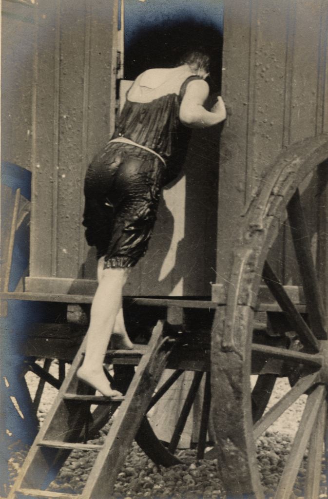 A woman enters a bathing machine after a swim.