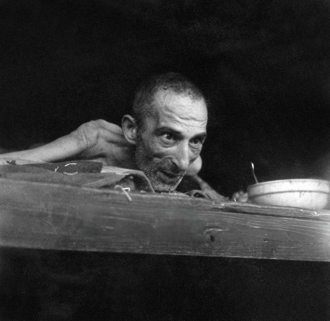 A prisoner dying of dysentery at the Nazi concentration camp of Buchenwald peers out from his bunk, 1945.