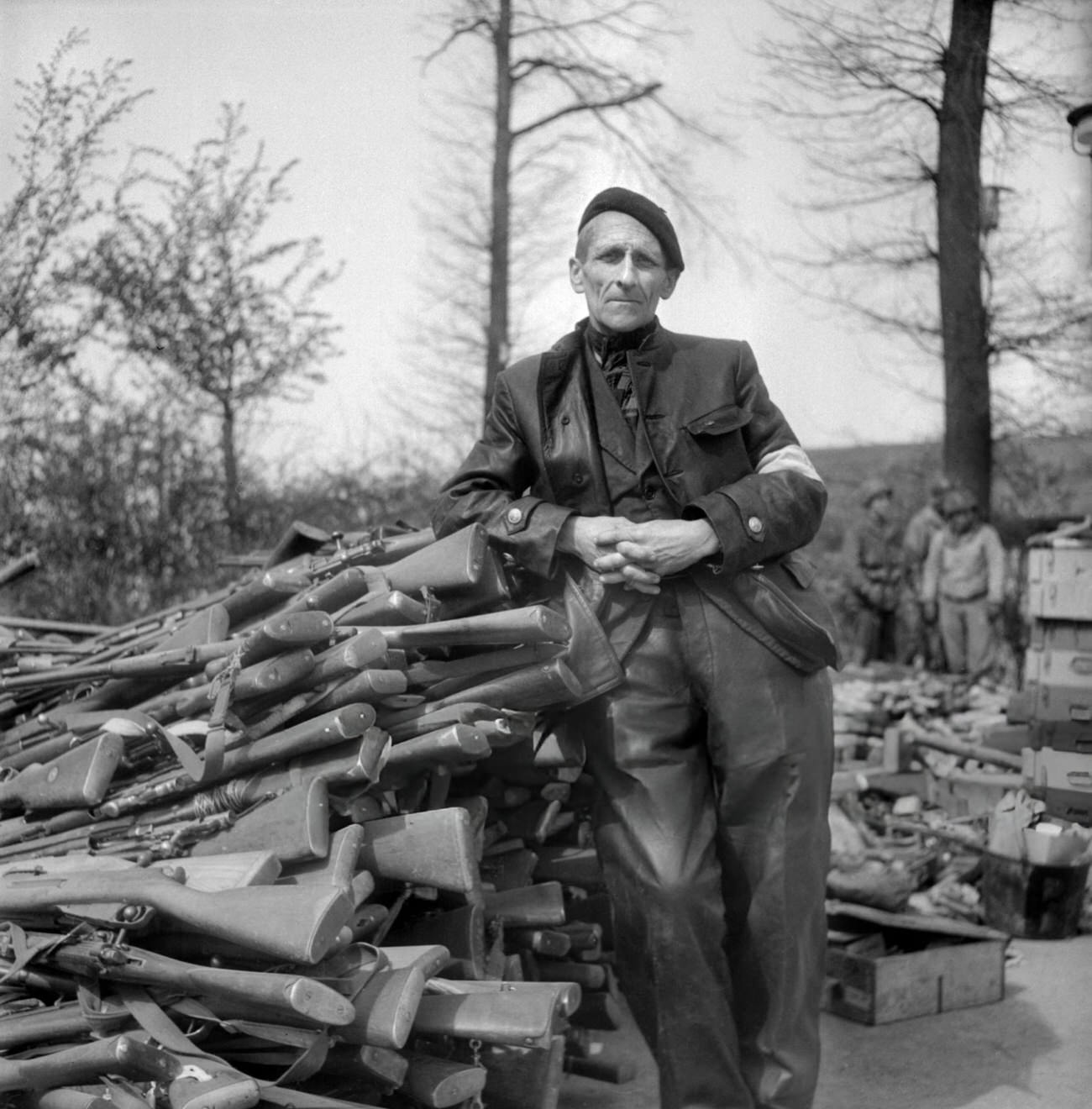 An unidentified man poses in front of pile of weapons in the courtyard of the Buchenwald Nazi concentration camp, 1945.