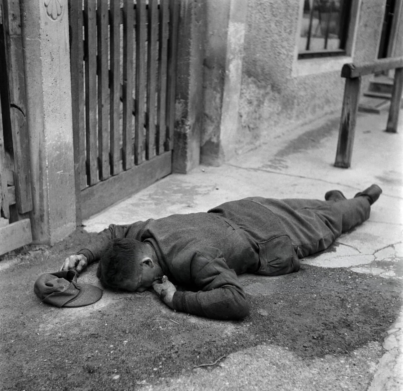 The body of a German soldier lies on the floor of the Dachau concentration camp after the US army liberated the camp, 1945.