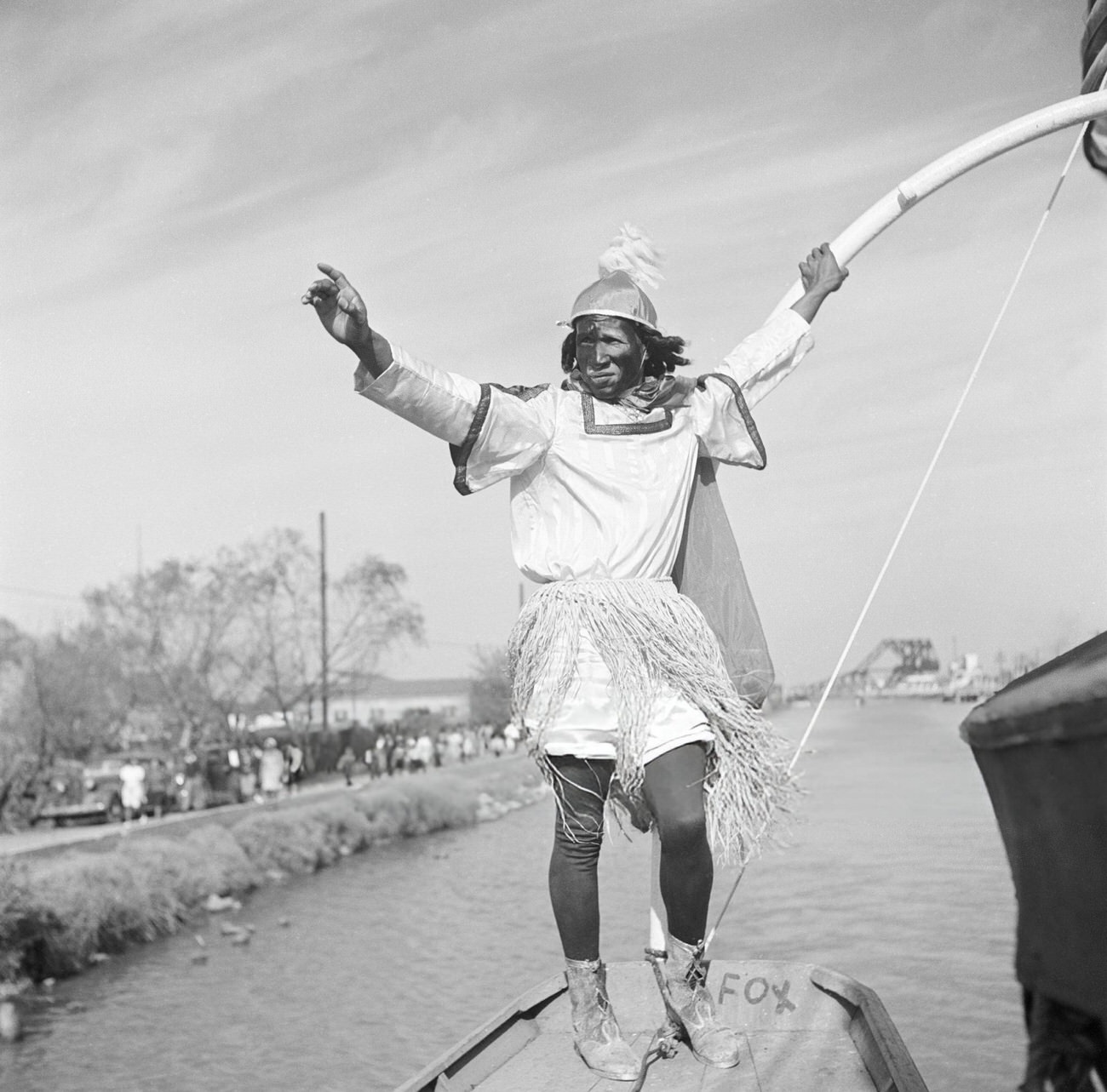 A Man in a Mardi Gras Boat Parade on a Canal Wearing a Costume and Carrying a Longbow Dances, 1950s.