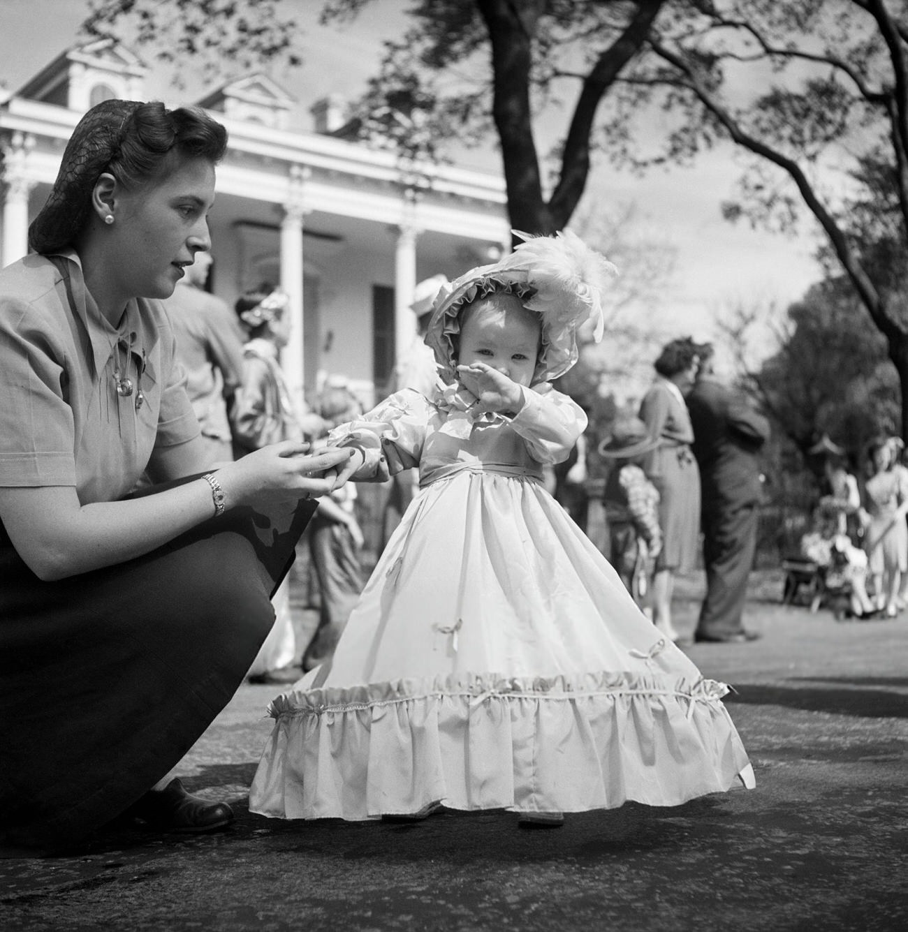 A Mother Guides Her Little Girl as She Toddles in Her Elaborate Mardi Gras Gown and Bonnet, 1950s.