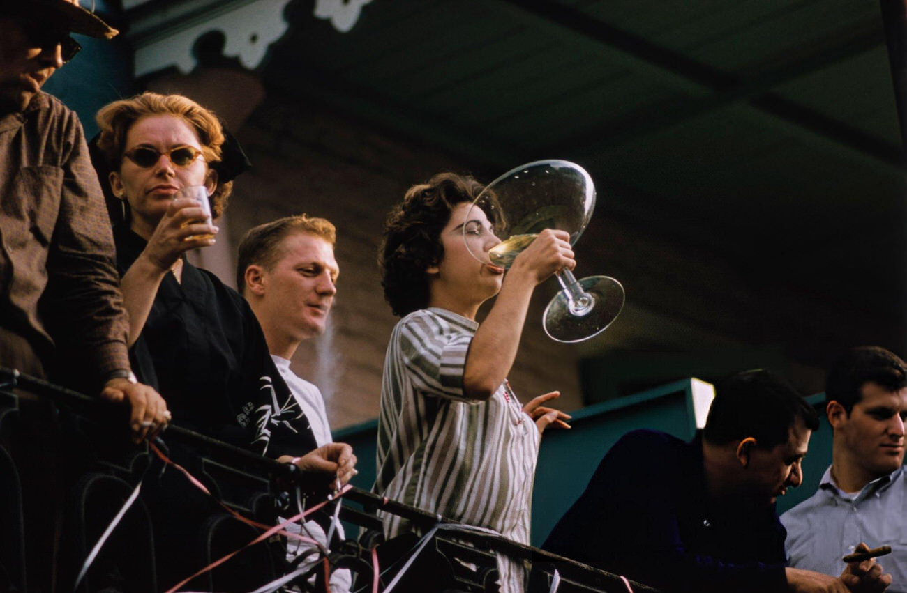 A Young Woman on a Balcony, Drinking From an Outsize Champagne Coupe During Mardi Gras in New Orleans, 1961.