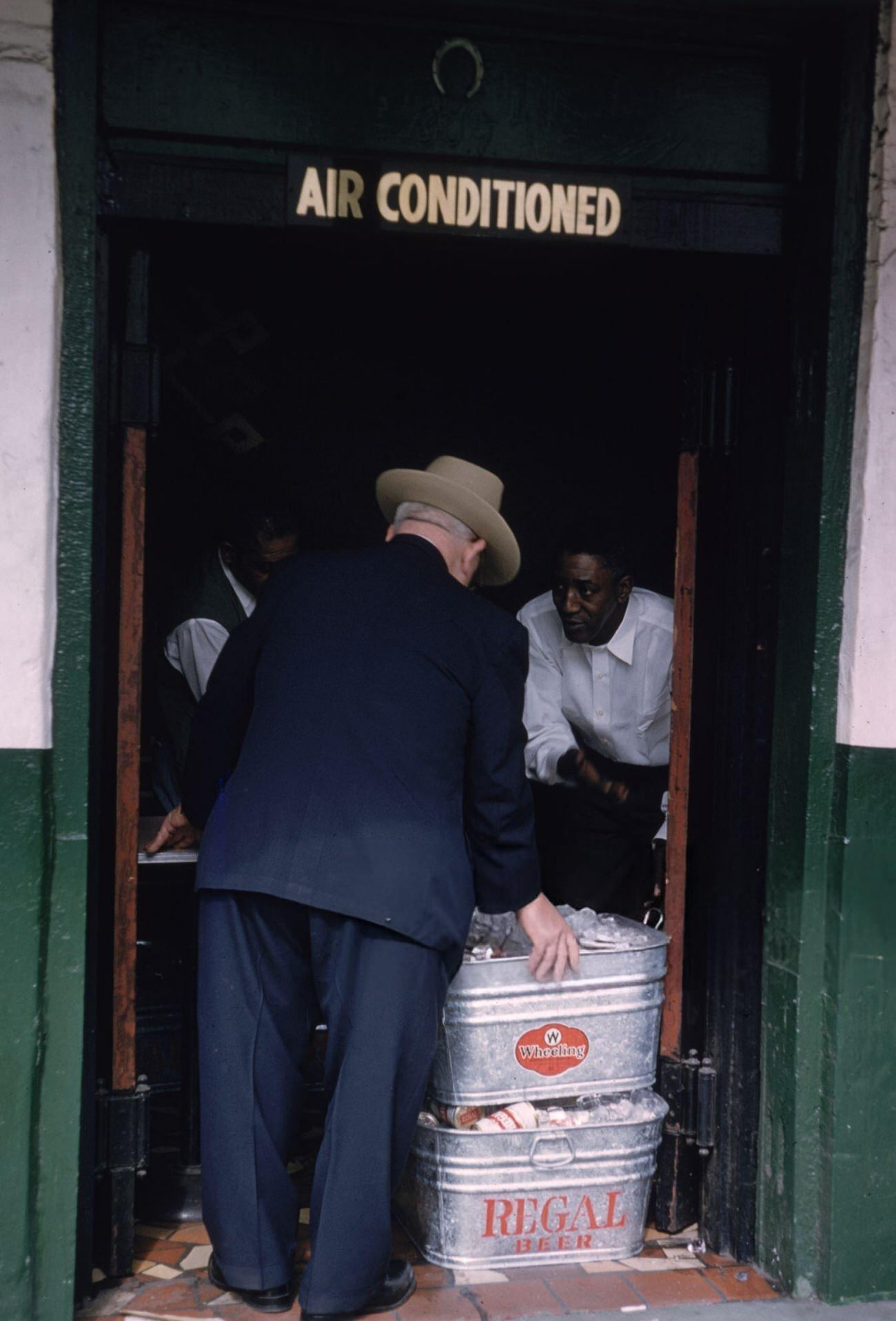 Cans of Beer Packed in Ice Are Being Inspected in a Doorway During Mardi Gras in New Orleans, 1961.