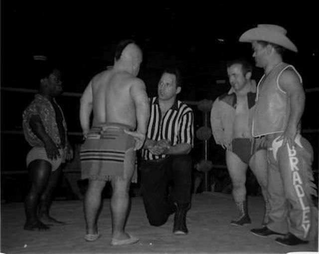 Referee George Gadaski talks to the legendary Little Beaver (back to camera) with tag partner Jamaica Kid to his left, and rivals Billy the Kid and Cowboy Bradley to his right.