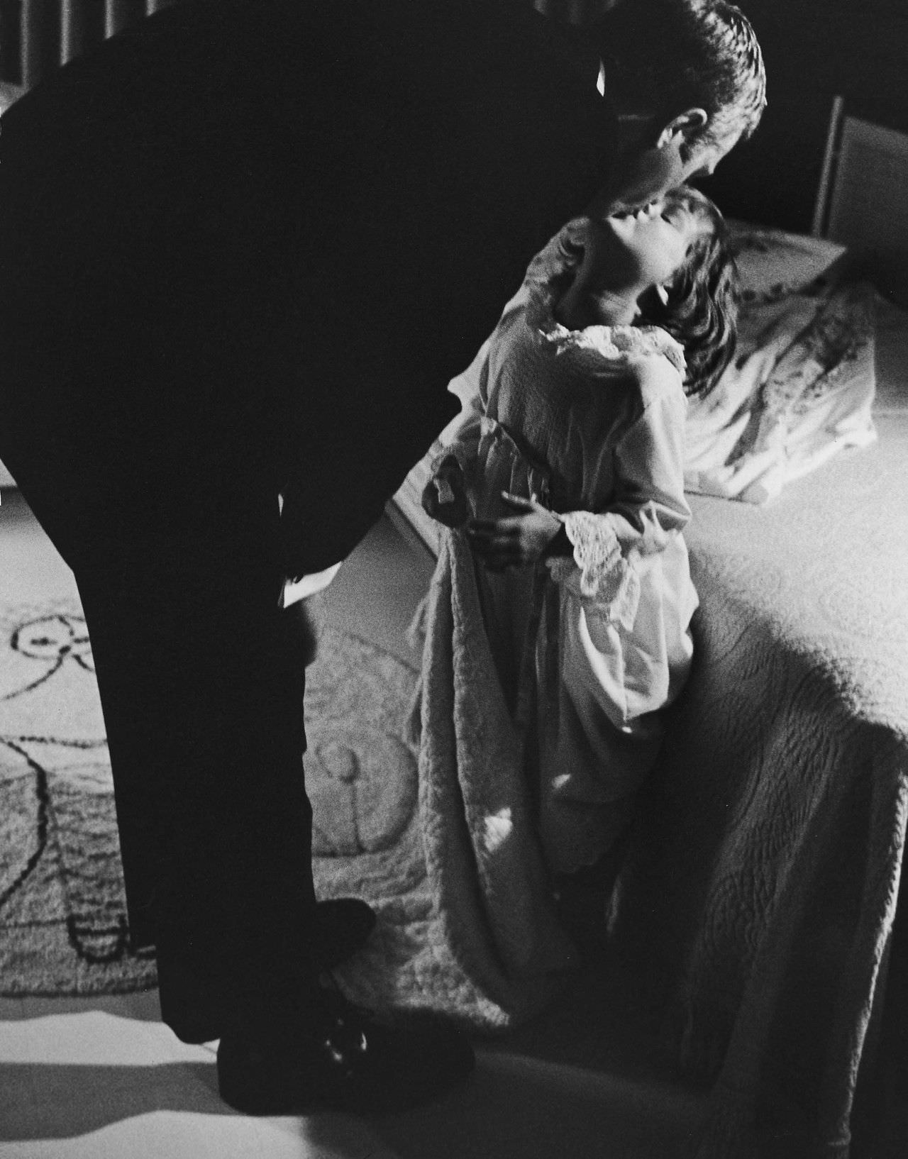 Steve McQueen kissing his daughter, Terry, goodnight, 1963.