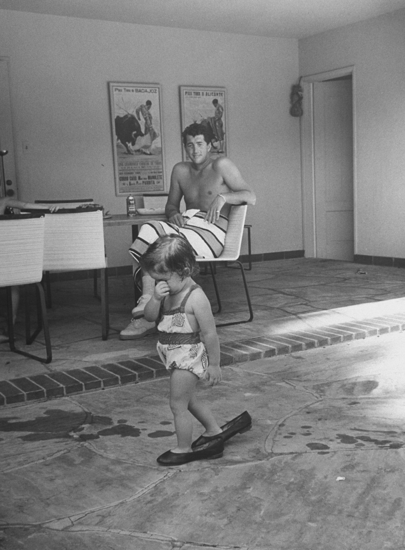 Dean Martin watches his daughter Gina Caroline Martin walking in his shoes, 1958.