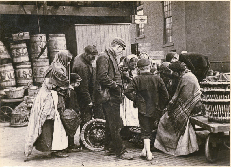 Quayside, possibly near the Fish Market, with a fish seller and a small crowd gathered around, 1880s.