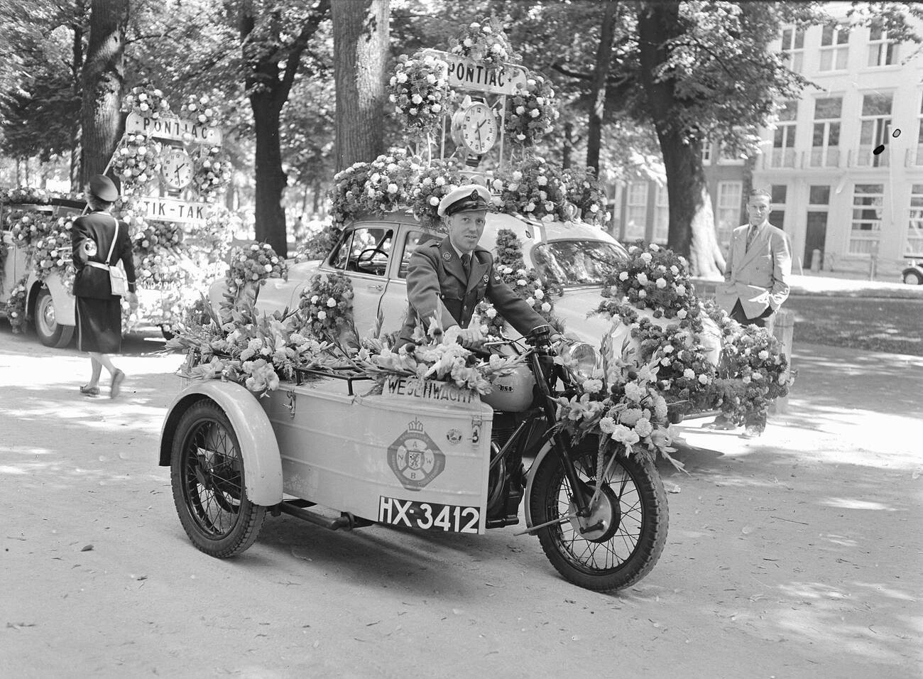 A patrolman on a decorated motorcycle with a sidecar at the Flower Parade in The Hague, 1953.