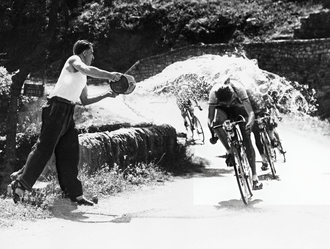 A spectator watering Dutch rider Jan Nolten during the Tour de France, 1953.