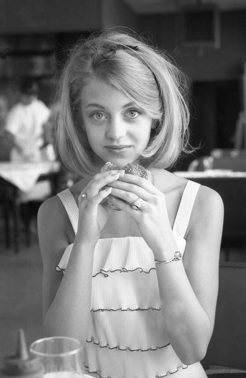 Goldie Hawn contemplating a hamburger. At a restaurant in Washington, DC, 1964