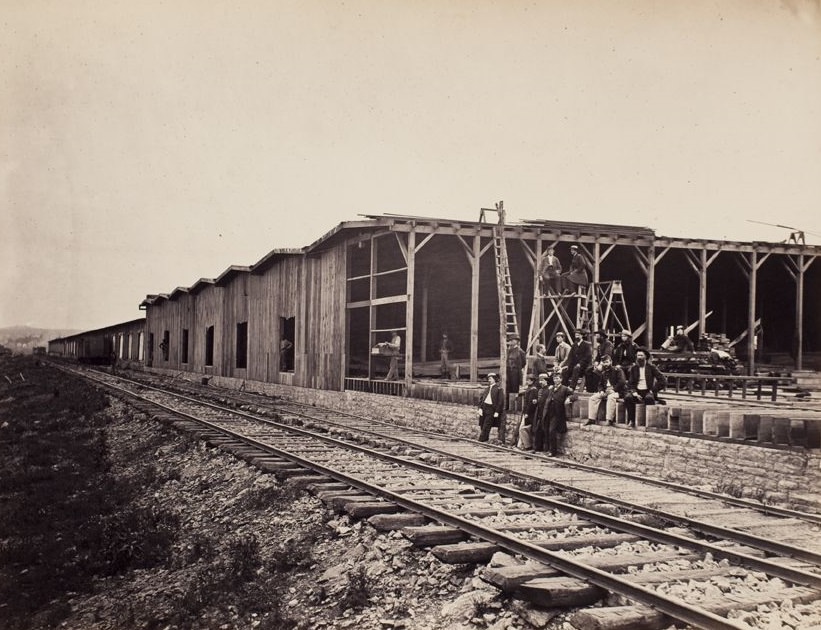 Men along railroad in front of warehouses under construction, 1865