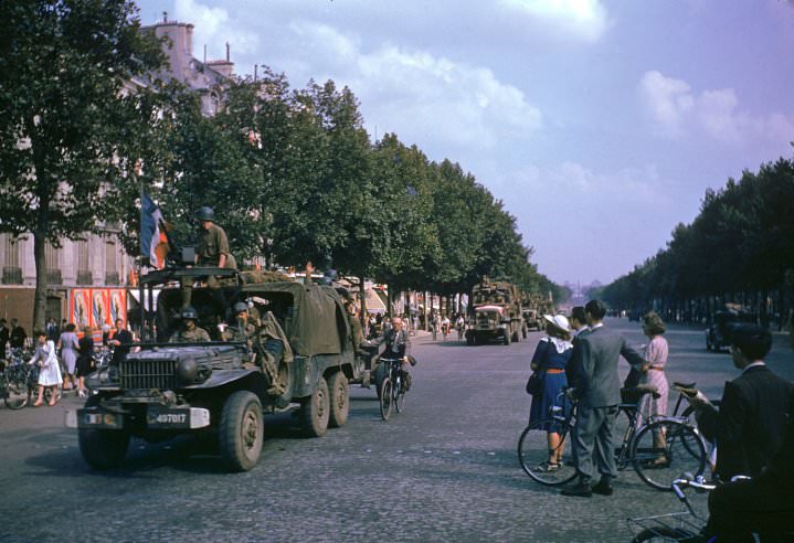 American Army trucks (note cyclist hitching a ride) parade down the Champs-Elysées the day after the liberation of Paris by French and Allied troops, August 1944