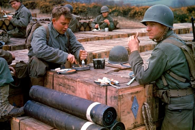 American combat engineers eat a meal atop boxes of ammunition stockpiled for the impending D-Day invasion, May 1944