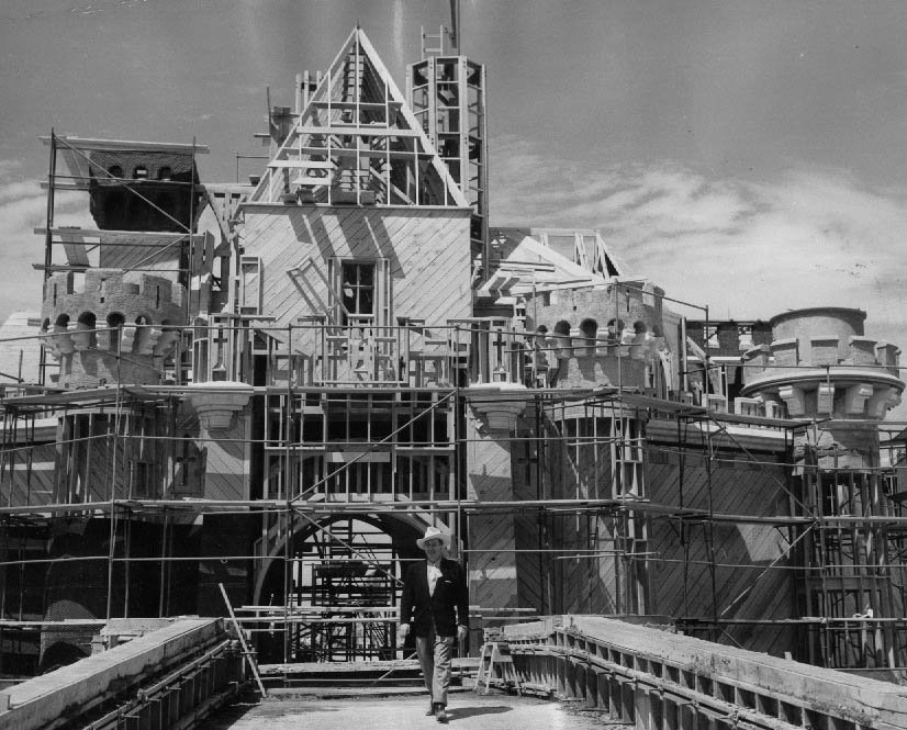 Walt Disney in front of a still-unfinished Sleeping Beauty's Castle, 1955