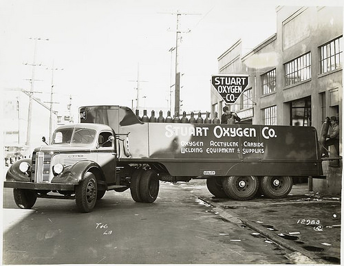 Model T 16 - L 8 in front of Stuart Oxygen Co. loading gas cylinders.