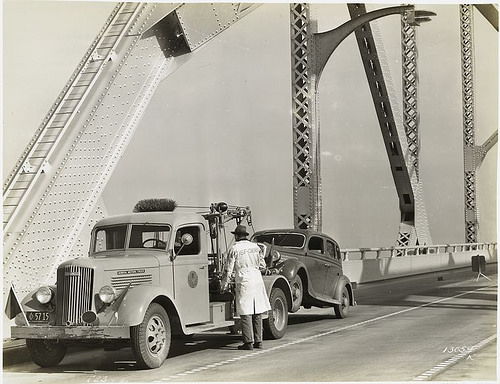 Model T 23 on a bridge with a man towing the car.