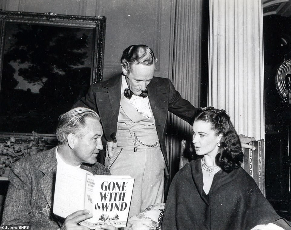 Director Victor Fleming holding the novel 'Gone With The Wind' while in discussion with Leslie Howard and Vivien Leigh.