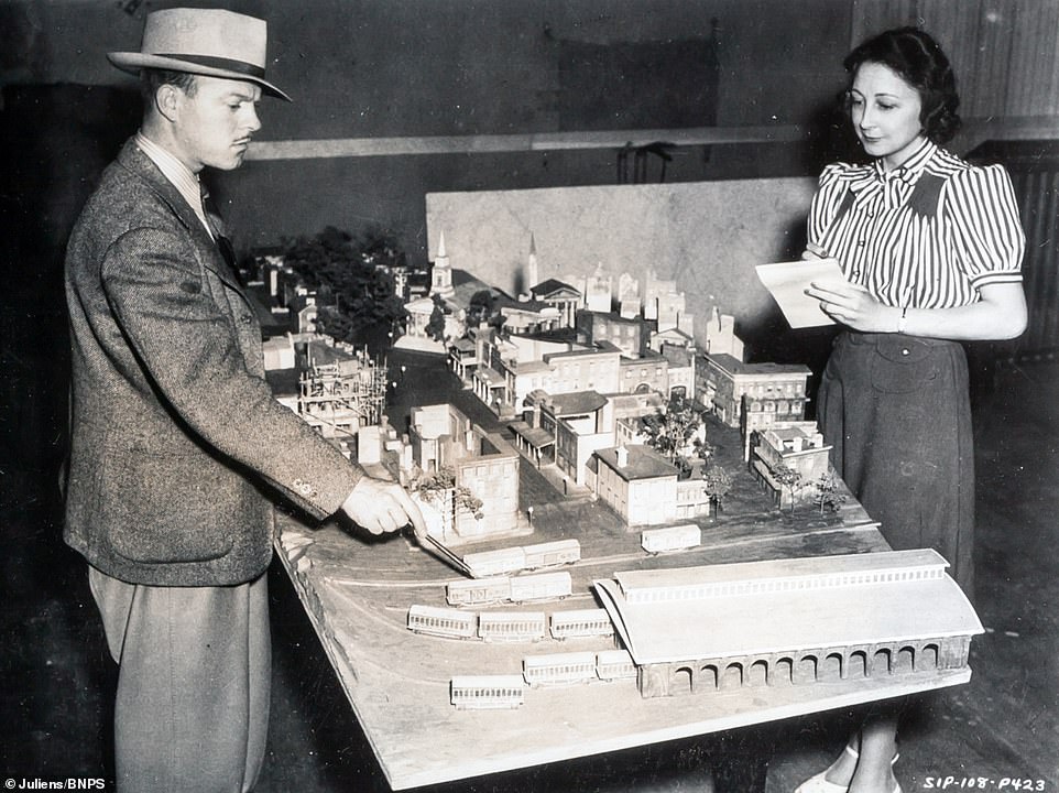 A behind the scenes shot of a location being discussed. On the centre of the table sits a diorama of a town with a railway depot.