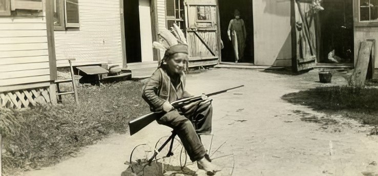 Boy in Indian costume on bike, 1950