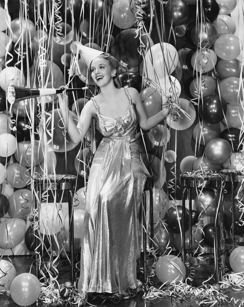 Woman celebrating with room full of balloons.