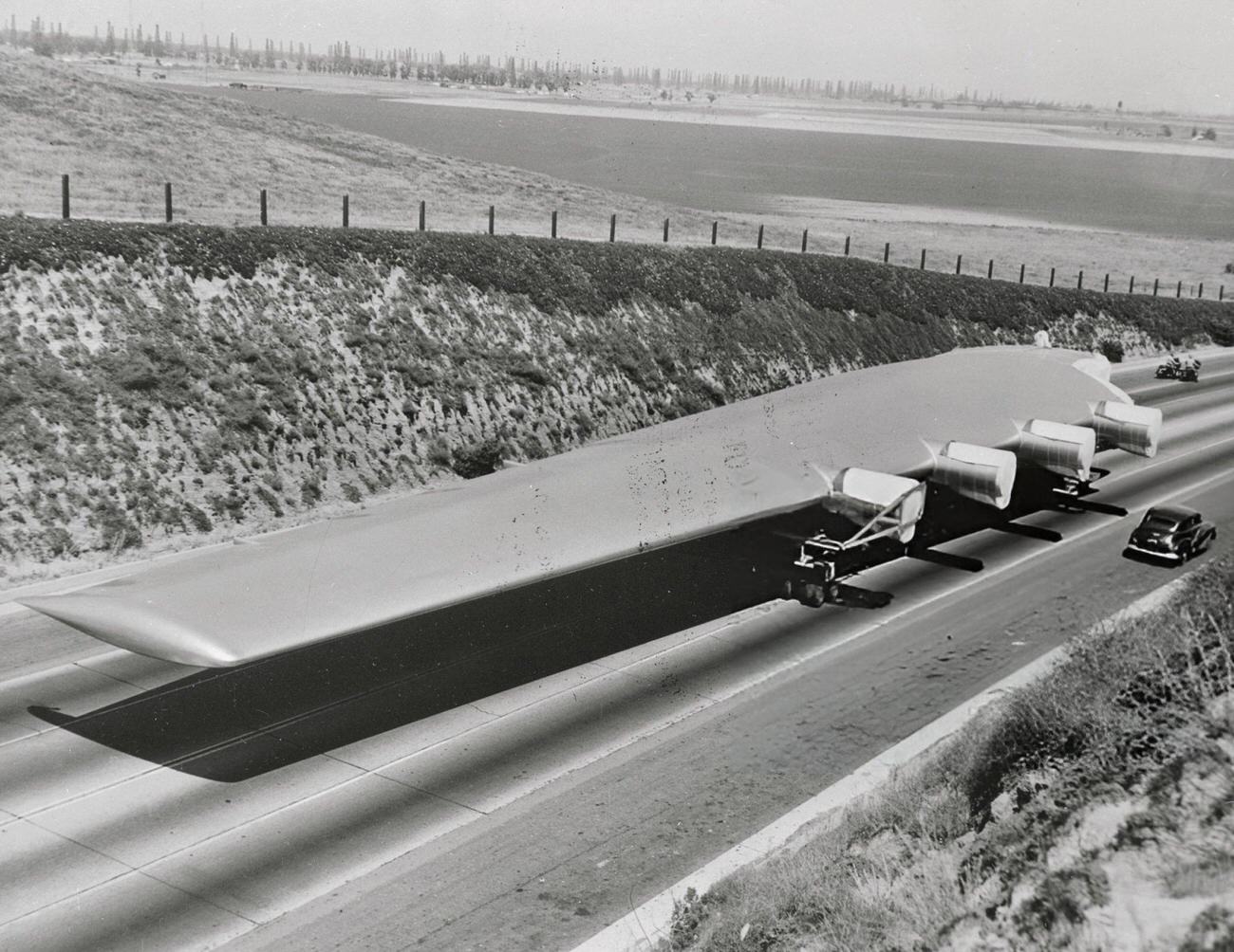 A Spruce Goose wing next to a car during transport, 1940s.