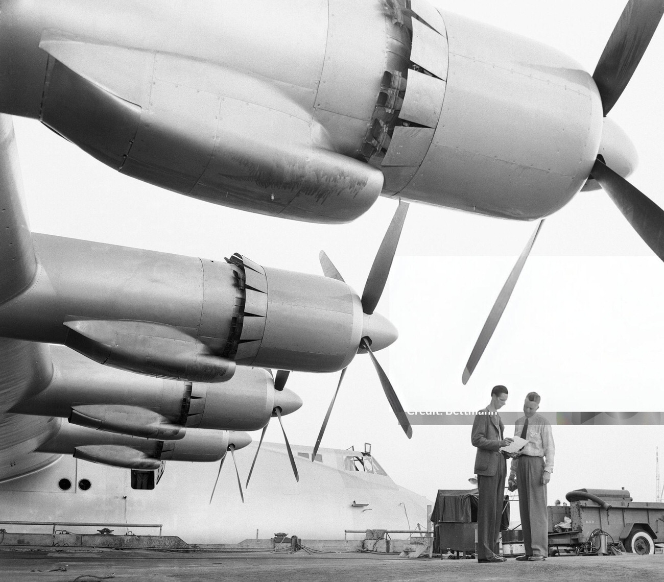 Two men dwarfed by the Spruce Goose's wing engines, 1947.